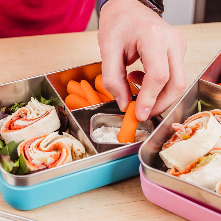 Child putting bento box in backpack with dad's help
