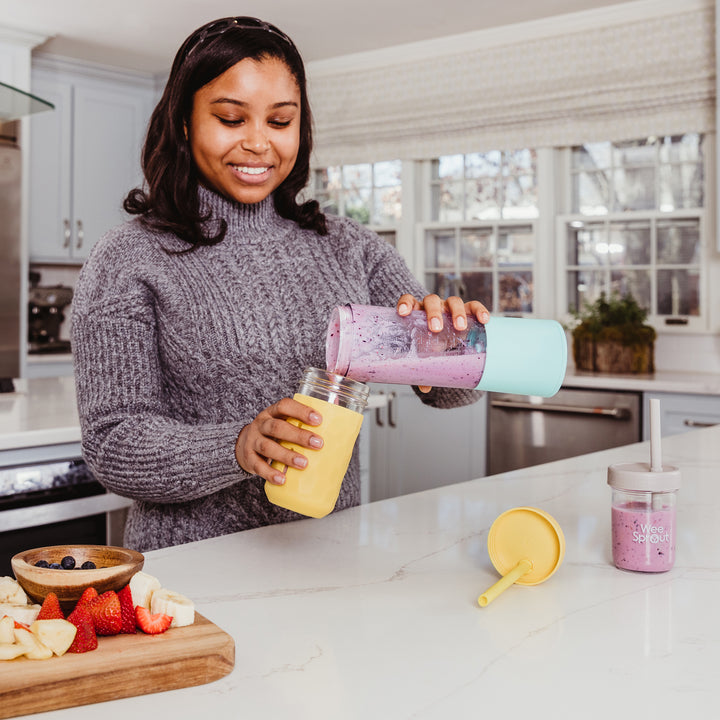 A woman filling up a Glass Drinking Jar with a purple smoothie