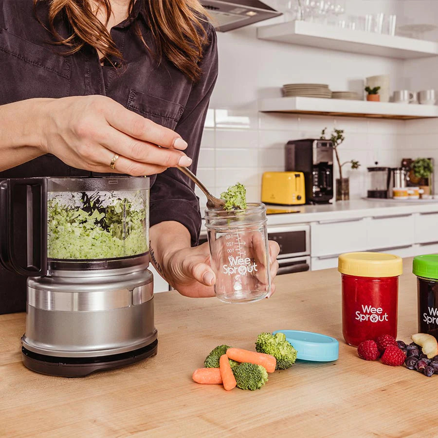 Mom blends broccoli and carrots into a purée and putting the mixture in a glass storage jar