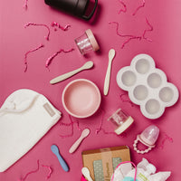 Baby starter products on a pink background with gift wrapping.