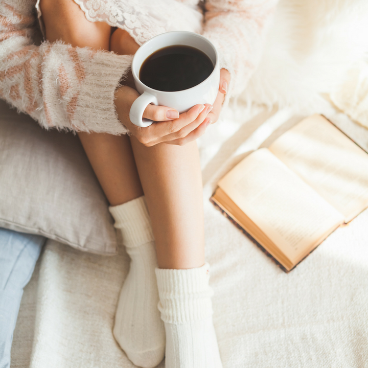 woman sitting with a cup of coffee and a book
