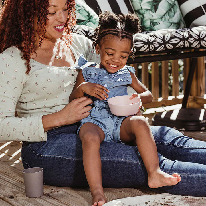 Mom feeds toddler out of gray and white bamboo toddler bowl and cup