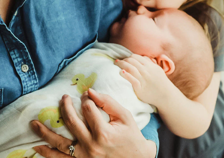 Mom holds baby wrapped in ducks swaddle