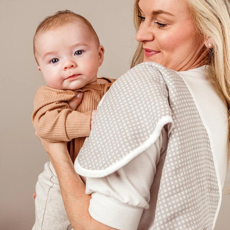 Baby looking while being snuggled by mom with a burp cloth on her shoulder