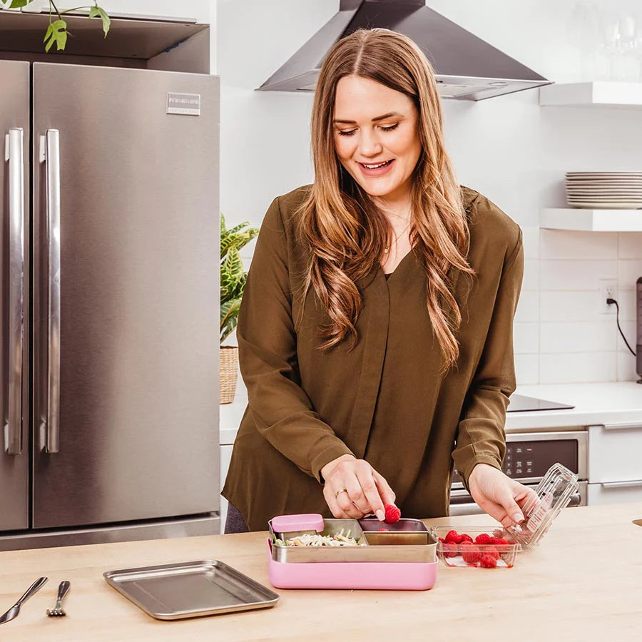 mom puts berries in large pink stainless steel bento box with sleeve