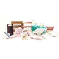 Baby product bundle on white background. Featuring baby glass food jars, nursing poncho, food pouches, thermos, baby spoons, silicone suction bowls, burp cloth, freezer tray, and baby food feeders.