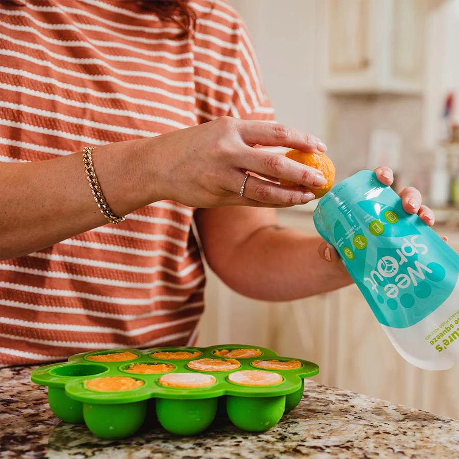 Mom loads frozen smoothie out of freezer silicone mold into reusable squeeze pouches
