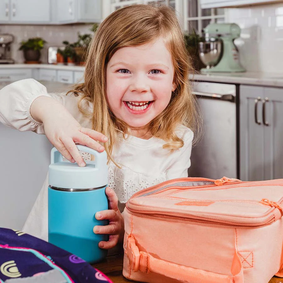 Child twists the lid on a blue thermos before putting it in her pink lunch box
