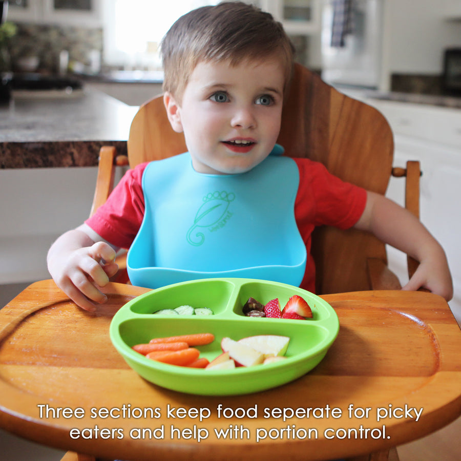 young boy eating from a green silicone divided toddler plate