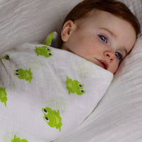Baby swaddled in a frog imprinted organic cotton blanket