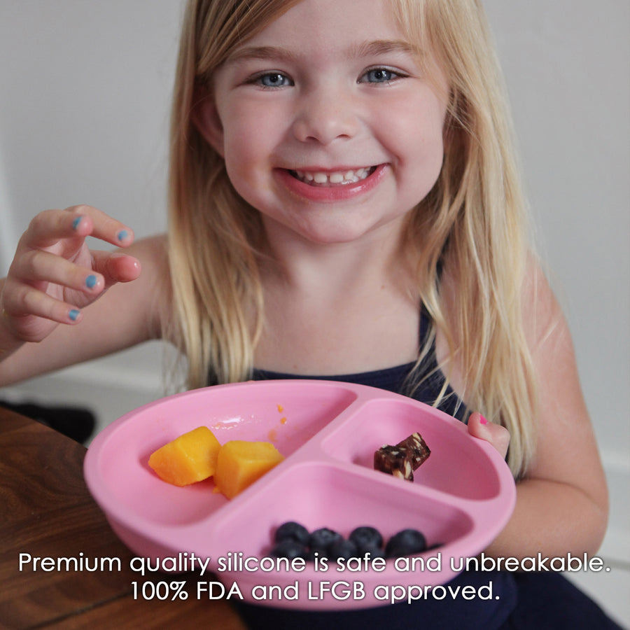 Young Girl eating off of a pink divided silicone plate for toddlers